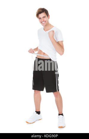 Ritratto di un felice Giovane misurando il suo girovita Foto Stock
