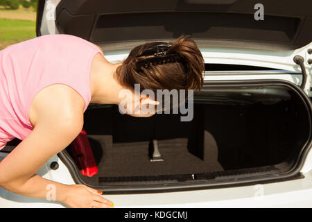 Giovane donna cercando nel baule auto Foto Stock