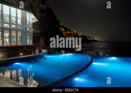 La piscina di un hotel di lusso shot di notte.piscina illuminata e oceano scuro in background Foto Stock