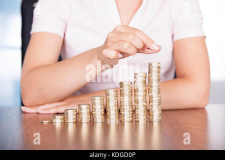 Close-up di imprenditrice di impilamento delle monete in oro su un aumento delle monete in euro Foto Stock