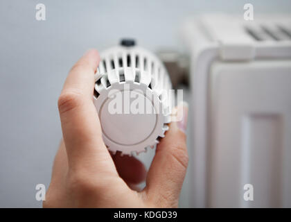 Donna lato regolazione della temperatura mediante termostato Foto Stock