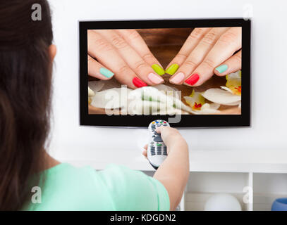 Close-up di una donna che mantiene il controllo remoto di cambiare canale televisivo Foto Stock