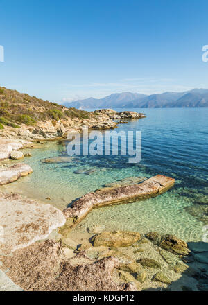 Vecchio molo di cemento e di calma e chiara del mar mediterraneo e piccola spiaggia sulla costa del deserto des Agriates vicino a St Florent in corsica con cap co Foto Stock