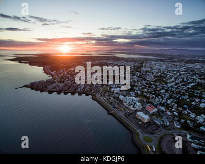 Vista aerea del sole di mezzanotte tramonto sulla città di Reykjavik in Islanda, girato dal sobborgo di hafnarfjordur affacciato sulla città verso la montagna ran Foto Stock