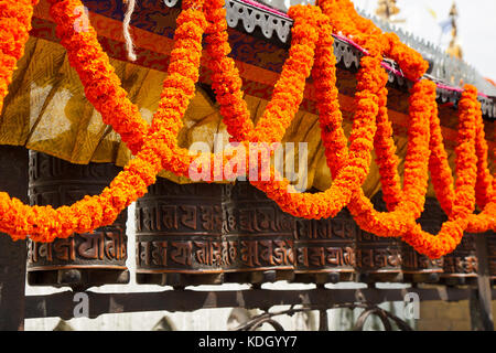 Swayambhunath. preghiera ruota, decorata con ghirlande di fiori. Foto Stock