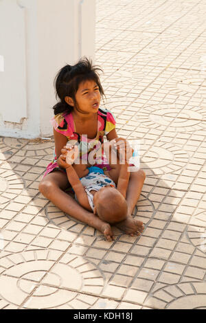 Phnom Penh Cambogia - febbraio 21, 2013: un bambino non identificato con un misterioso bambino seduto a mendicare per denaro sulla strada di phnom penh Foto Stock