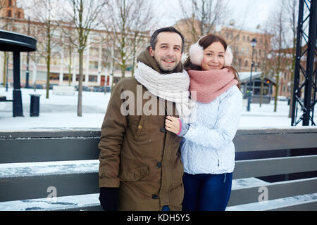 Felice coppia attiva in winterwear trascorrere del tempo sulla pista di pattinaggio Foto Stock