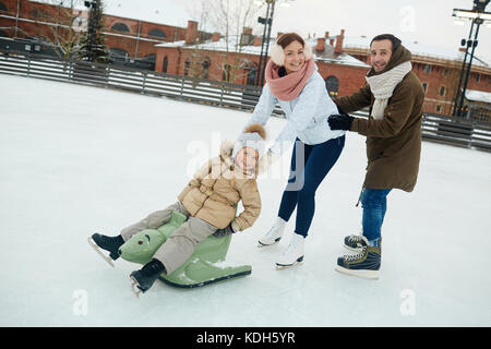 Gioiosa famiglia di tre divertirsi sulla pista di pattinaggio sulla giornata invernale Foto Stock