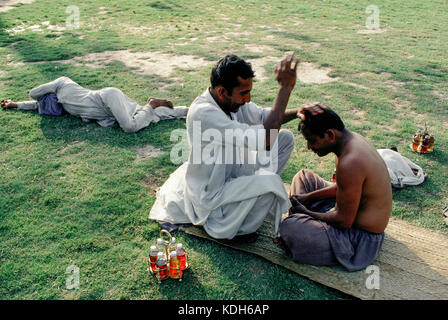 Una testa massaggiatore dà un massaggio nella motivazione del Shah Rukn-e-Alam, santuario di Multan, in Pakistan. Foto Stock