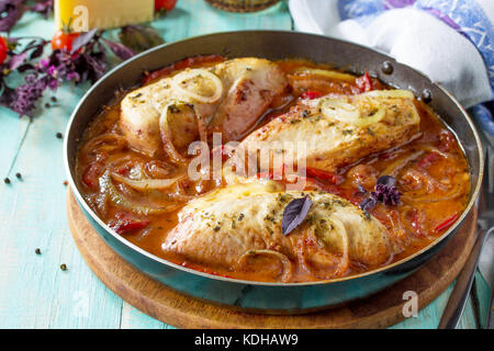 Il pollo al forno farcito con pomodoro e formaggio in una padella sul tavolo della cucina. Foto Stock