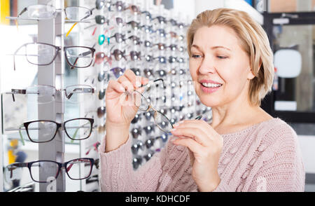 Coppia positiva bionda femmina l'acquisto di occhiali presso il display Foto Stock