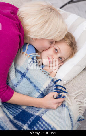 Vista superiore della madre baciando la sua piccola figlia malati. Foto Stock