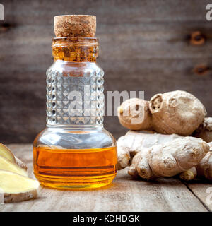 Medicina alternativa e natura terme ingredienti . di radice di zenzero e lo zenzero olio essenziale impostato sul vecchio tavolo in legno. Foto Stock