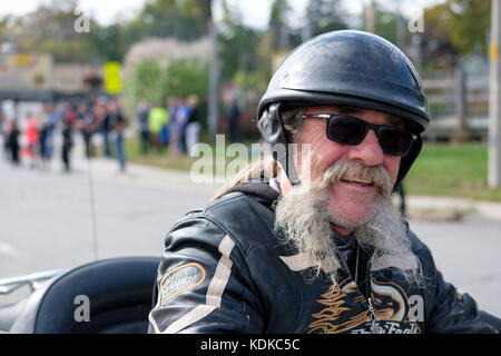 Porto di Dover, Ontario, Canada, 13 ottobre 2017. Migliaia di motociclisti da tutto il Canada e gli stati uniti insieme per il venerdì il tredicesimo Raduno motociclistico, che si tiene ogni venerdì il tredicesimo nel porto di Dover, Ontario, Canada, dal 1981. L'evento è uno dei più grandi a singolo giorno motociclo eventi in tutto il mondo. Il clima mite hanno contribuito per un gran numero di motociclisti e curiosi, con centinaia di motociclette personalizzate, fornitori di musica dal vivo e persone interessanti da guardare. Di mezza età biker maschio con barba grigia che indossa un casco, occhiali da sole, sorridente alla fotocamera. Credito: Rubens Alarcon/Alamy Live News Foto Stock