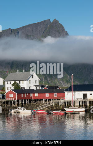 Pescatore tradizionale rorbu, cottage, capanne in isole Lofoten. maestose montagne e nuvole in background Foto Stock