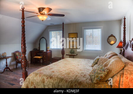 Camera da letto con letto a baldacchino, comodino, ventilatore a soffitto, pavimento in legno duro e sala da bagno privata in una lussuosa casa in Vermont, USA. Foto Stock