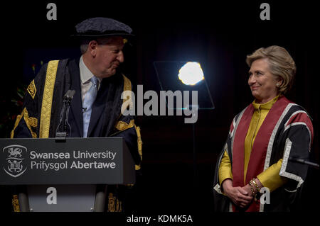 Hillary Clinton scherza con il Vice Cancelliere Professor Richard Davies, in quanto riceve un dottorato onorario presso l'Università di Swansea, in riconoscimento del suo impegno a promuovere i diritti delle famiglie e dei bambini in tutto il mondo, Un impegno condiviso dall'Osservatorio sui diritti umani dei bambini e dei giovani della Swansea University. Foto Stock