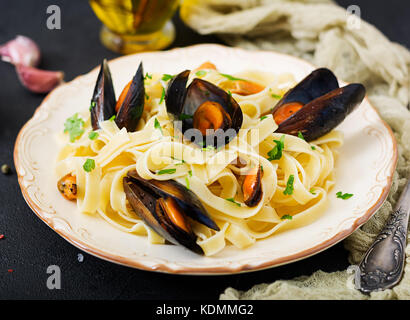 Frutti di mare fettuccine con cozze su sfondo nero. mediterraneo la delicatezza del cibo. Foto Stock