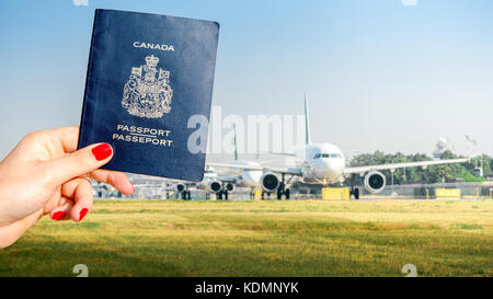 Composito digitale di avere un passaporto canadese con una fila di aerei commerciali su tassare su asfalto - concetto di viaggio Foto Stock