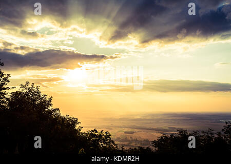 Ispirato tramonto paesaggio, Mountain View Point. Cerca e la pianura della valle del villaggio e dalla collina di picco. Sun e drammatici nuvole sopra la foresta, Polonia. Foto Stock