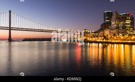 Riflessioni del ponte della baia di san francisco ed il lungomare visto dal pier 14 a sunrise. Foto Stock