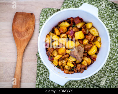 Cucina francese lardons - fritto di maiale tagliata a cubetti pancia , pancetta e tagliate a cubetti di patate con timo ,le foglie di alloro e galic in una ciotola bianco impostato sul tavolo di legno flat Foto Stock