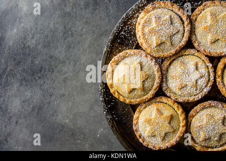 Tradizionale natale britannico pasticceria dolce cotto domestico pasticci di carne macinata con apple uvetta dadi riempimento frolla dorata in polvere vintage sulla piastra metallica d Foto Stock