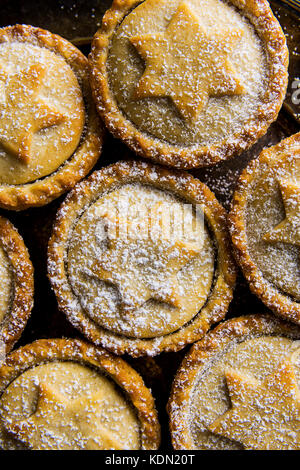 Tradizionale natale britannico pasticceria dolce cotto domestico pasticci di carne macinata con apple i dadi di uva passa dorata di riempimento frolla pattern in polvere vista superiore festive Foto Stock