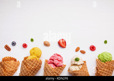 Colorato gelati con coni e frutti vari ,Lampone Mirtillo ,fragola ,le mandorle e le foglie di menta piperita setup su sfondo bianco . estate un Foto Stock