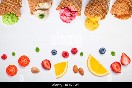 Colorato gelati con coni e frutti vari ,Lampone Mirtillo ,fragola ,le mandorle e le foglie di menta piperita setup su sfondo bianco . estate un Foto Stock