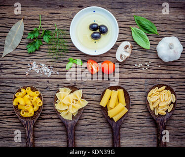 Vari tipi di pasta di pasta tipo gramigna,farfalle,rigatoni,gnocco sardo in cucchiaio con ingredienti basilico dolce ,il pomodoro , Aglio , Olio di oliva extra vergine , par Foto Stock