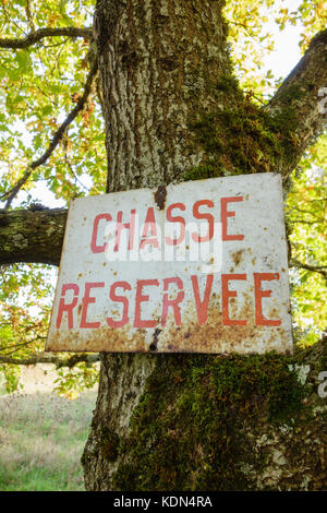 Segnale di avviso in un albero. segno di caccia in francese, "chasse réservée' riservato a caccia scritto su un arrugginito foglio di metallo. Francia, Cher. Foto Stock