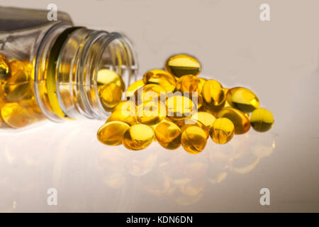 Olio di pesce capsule/ Supplemento di assistenza sanitaria/ con acidi grassi Omega 3 fuoriuscita dalla bottiglia trasparente Foto Stock