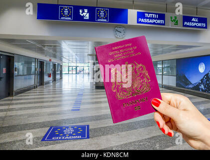 Persona in possesso di un passaporto britannico nella zona di controllo dei passaporti aeroportuali, formato digitale Foto Stock