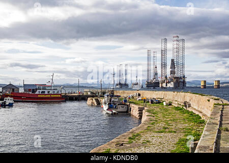 Porto di Cromarty con traghetto Nigg Renfrew Rose e ormeggiato piattaforme petrolifere in Cromarty Firth a Cromarty Black Isle Scotland Regno Unito Foto Stock