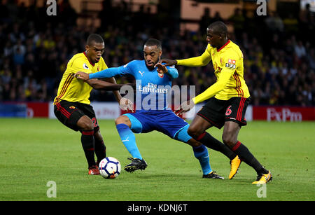 Alexandre Lacazette (centro) dell'Arsenal si batte per il pallone con Abdoulaye Doucoure (destra) di Watford e Christian Kabasele (sinistra) durante la partita di Premier League a Vicarage Road, Watford. Foto Stock