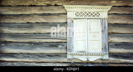 Finestra chiusa in casa abbandonata. telaio di legno con architravi e persiane. facciata di un vecchio log cabin. viaggio al nord della Russia. kenozersky n Foto Stock