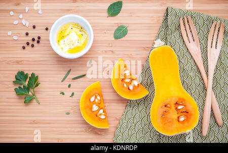 Cibo sano e concetto di cucina a vista. ingredienti per la zuppa di zucca in bambù tagliere. fresca fetta di zucca con il burro non salato e erbe rosmarino ,l Foto Stock