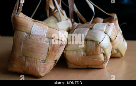 Ketupat, tradizionali torte di riso. Un tipo di gnocco fatto dal riso imballate all'interno di un diamante-contenitore sagomato in tessuto di foglia di palma custodia. servita su specia Foto Stock