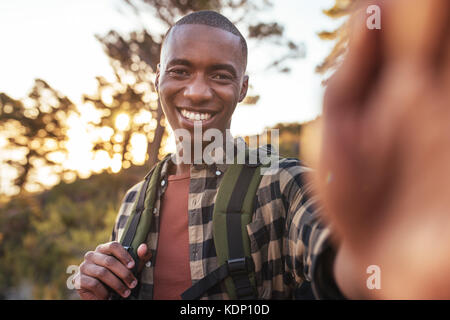 Sorridente giovane africano tenendo selfies mentre fuori escursionismo Foto Stock