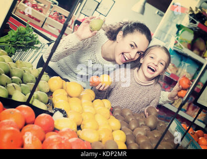 Allegro Giovane Donna con bambina acquisto di frutta al mercato Foto Stock