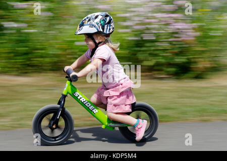 Una bambina di tre anni in sella a una moto di equilibrio Foto Stock