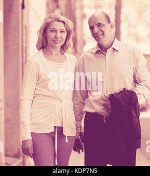 Passeggiate attraverso la strada della famiglia senior giovane tenendo le mani di ciascuno e parlare Foto Stock