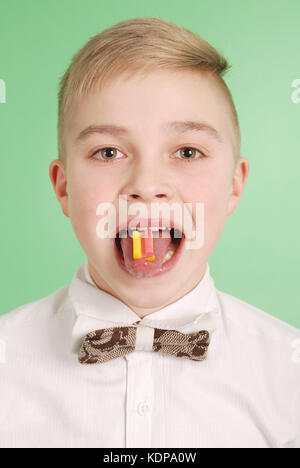 Ragazzo giovane mettere la gomma da masticare sulla sua linguetta isolata su sfondo verde Foto Stock