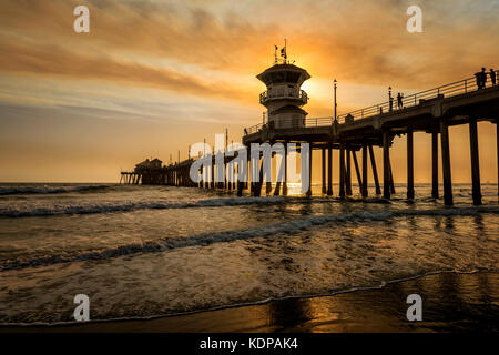 I fuochi selvatici locali pipelano fumo marrone dorato sopra i cieli del molo di Huntington Beach, creando paesaggi surreali. Foto Stock