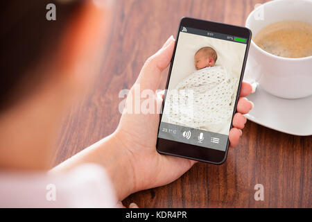 Close-up di persona la mano guardando al bambino il babyphone Foto Stock