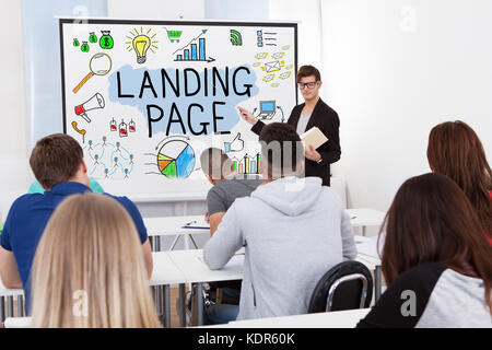 Insegnante maschio che spiega il concetto di landing page per gli studenti in aula Foto Stock