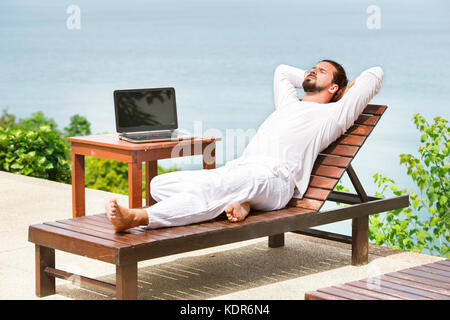 Imprenditore bianco da indossare con computer portatile sulla spiaggia Foto Stock