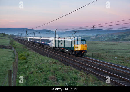 Il 2350 London Euston - Glasgow & Edinburgh Caledonian Sleeper treno passa Salterwath (sud di Shap) all'alba a metà estate Foto Stock