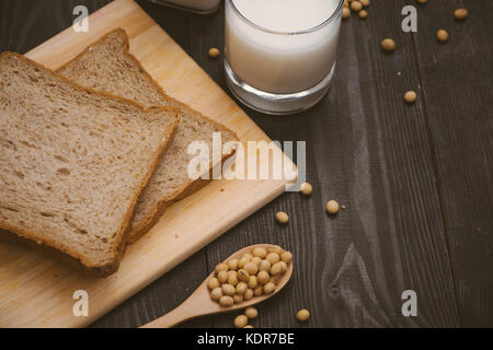 La prima colazione con i fagioli di soia in cucchiaio, latte di soia e sandwich su sfondo di legno Foto Stock